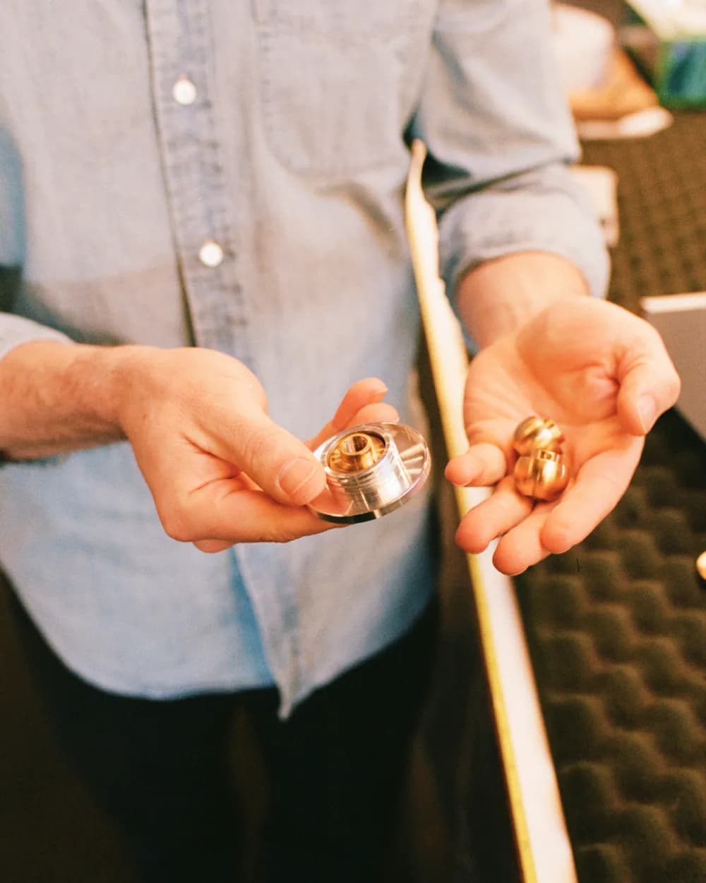 Hands holding machined metal canopy hardware and brass components beside a length of cord
