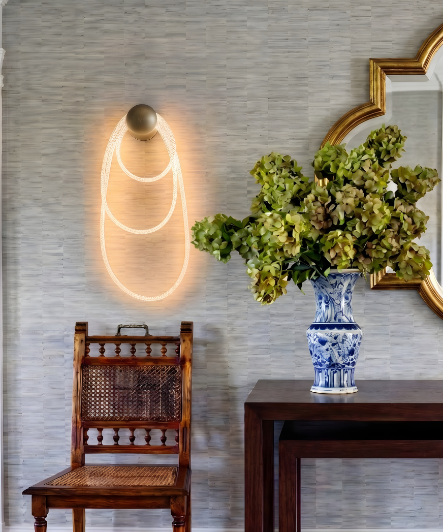 Traditional console vignette with mirror and floral arrangement, featuring a wall-mounted sconce with brass anchor and softly looping illuminated rope detail.